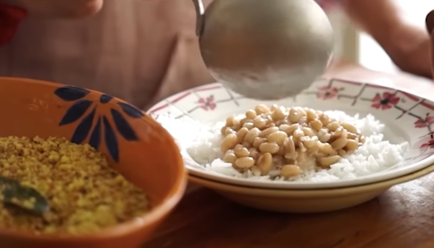 Prato com arroz e feijão ao lado de uma travessa com farofa